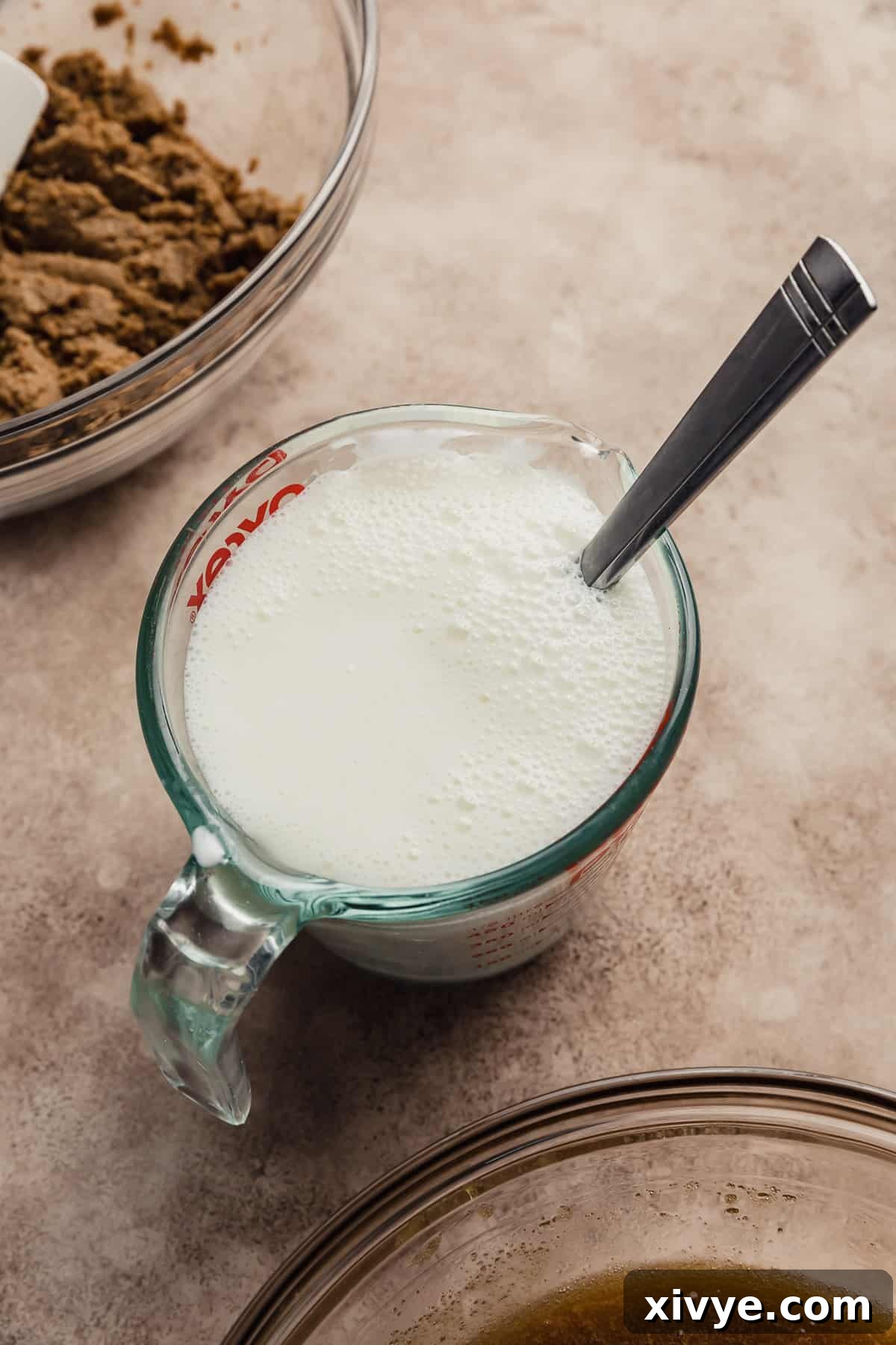 Hearty Buttermilk Bran Muffins 8 A glass measuring cup filled with buttermilk and baking soda, with it slightly foaming.