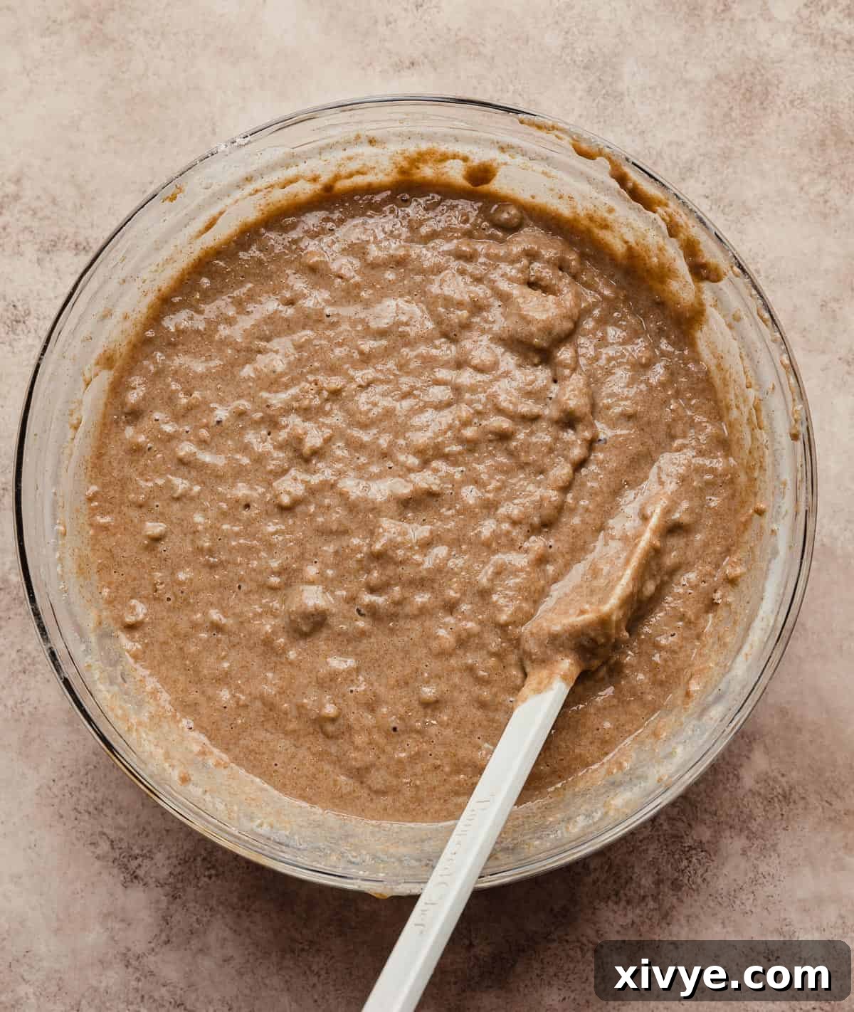 Hearty Buttermilk Bran Muffins 10 All Bran Muffins with buttermilk batter in a glass bowl on a light brown textured background.