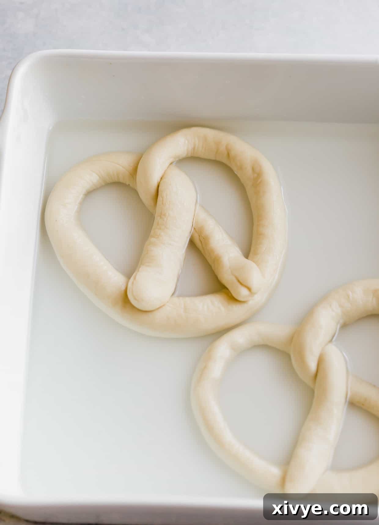 Pillowy Homemade Soft Pretzels 7 An unbaked pretzel in a baking soda and water bath.