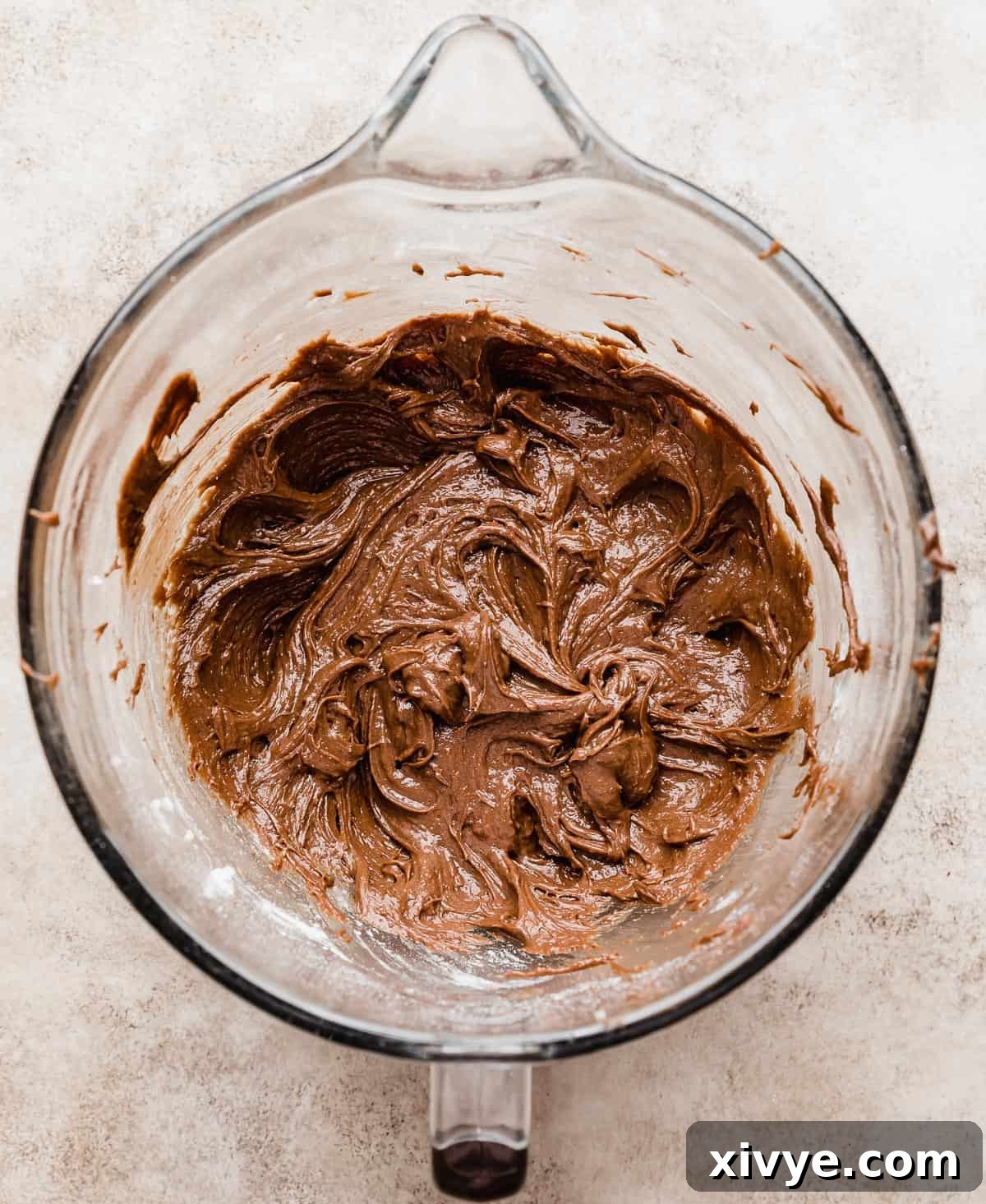 Ferrero Rocher Brownie batter in a glass bowl on a light beige background.