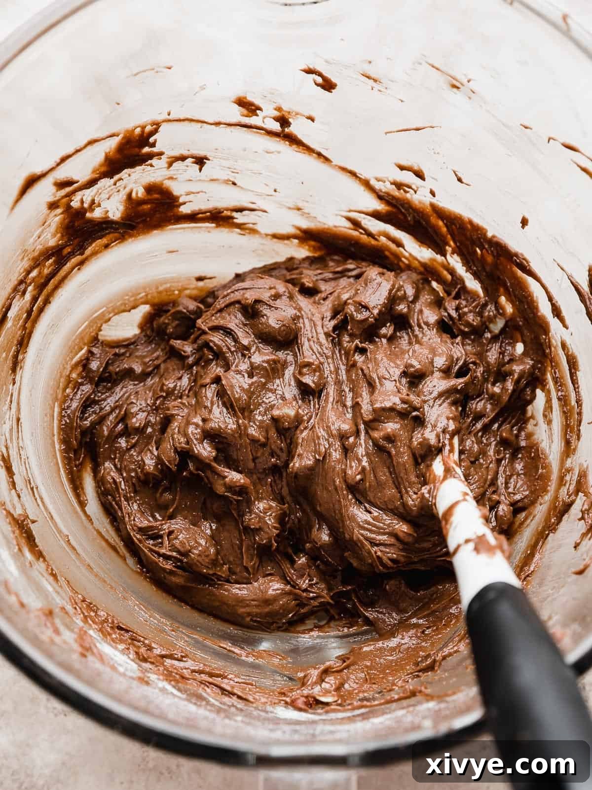 Close up photo of Ferrero Rocher Brownie batter with chopped hazelnuts and milk chocolate in the batter.