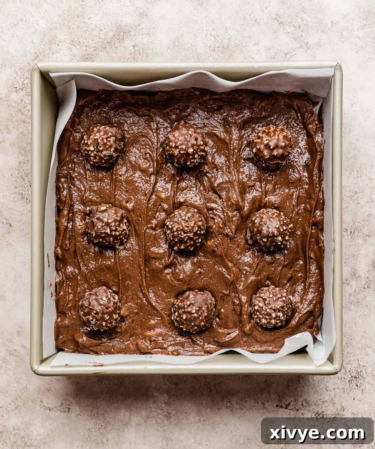 9 Ferrero Rocher's stuck on the top of brownie batter in a square pan.