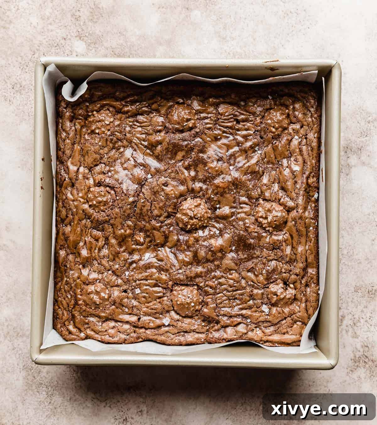 Ferrero Rocher Brownies with a crackly baked top, on a beige textured background.
