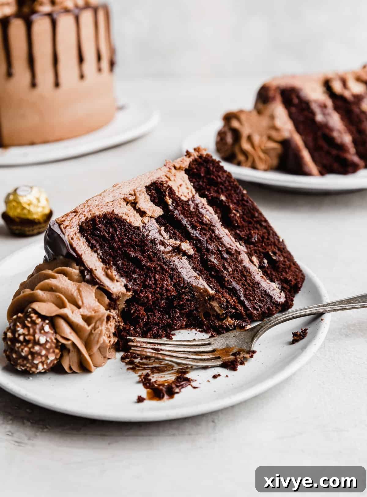 Ultimate Ferrero Rocher Indulgence 12 A chocolate hazelnut layer cake on a white plate with a fork next to the slice.