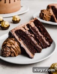 Ultimate Ferrero Rocher Indulgence 13 A slice of Ferrero Rocher Chocolate Hazelnut Cake on a white plate against a white background.