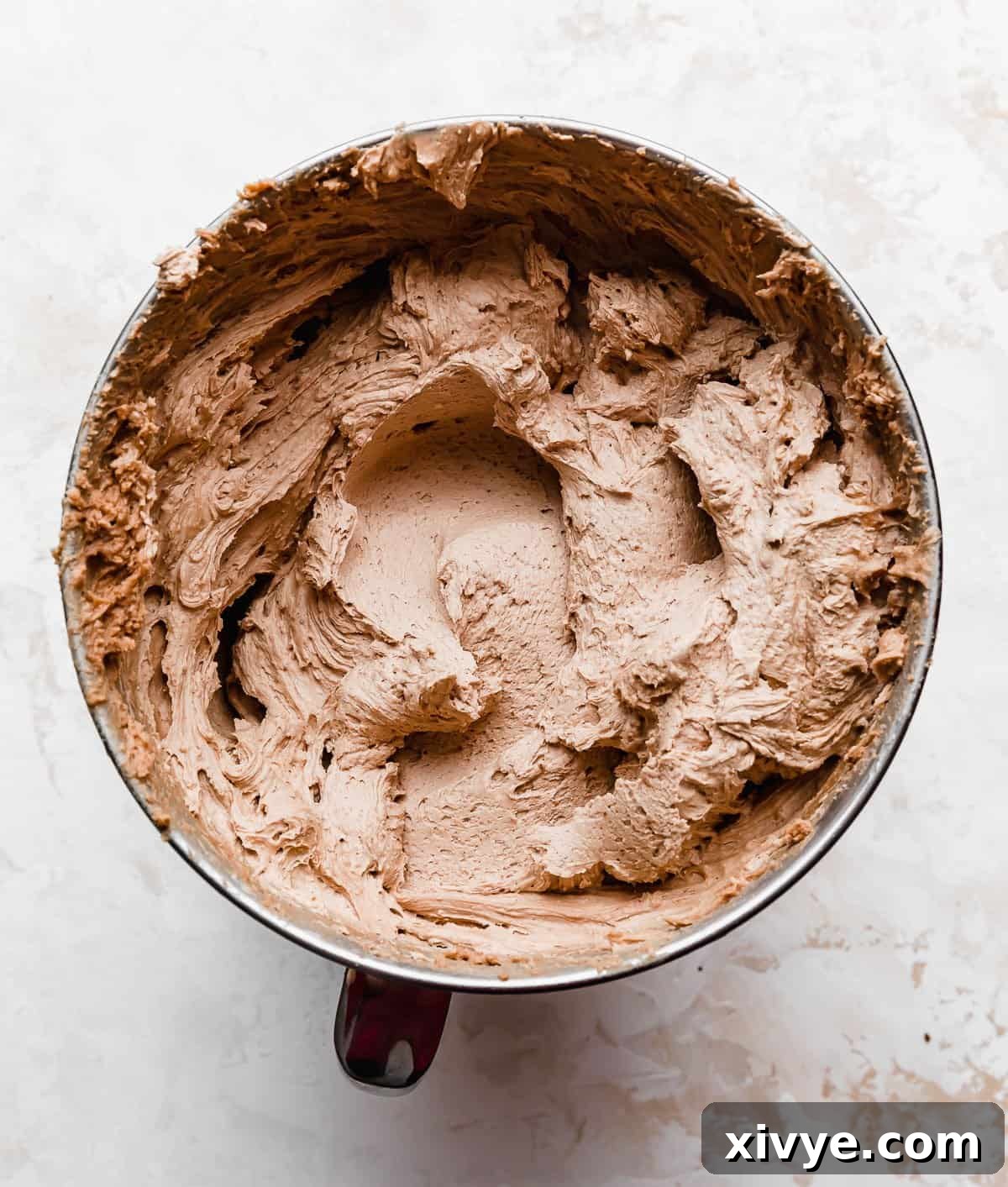 Ultimate Ferrero Rocher Indulgence 7 Chocolate buttercream frosting in a metal stand mixer bowl on a white background.