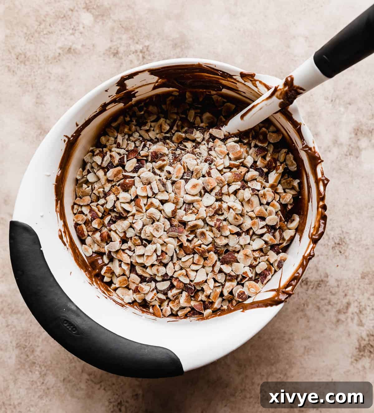 Ultimate Ferrero Rocher Indulgence 5 A white bowl full of Nutella whipped cream with chopped hazelnuts overtop.