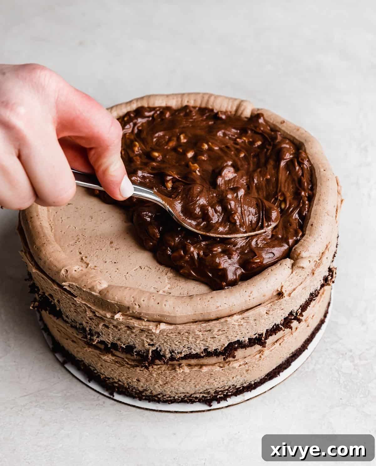 Ultimate Ferrero Rocher Indulgence 9 A hazelnut Nutella filling being spread over a chocolate frosting topped cake.