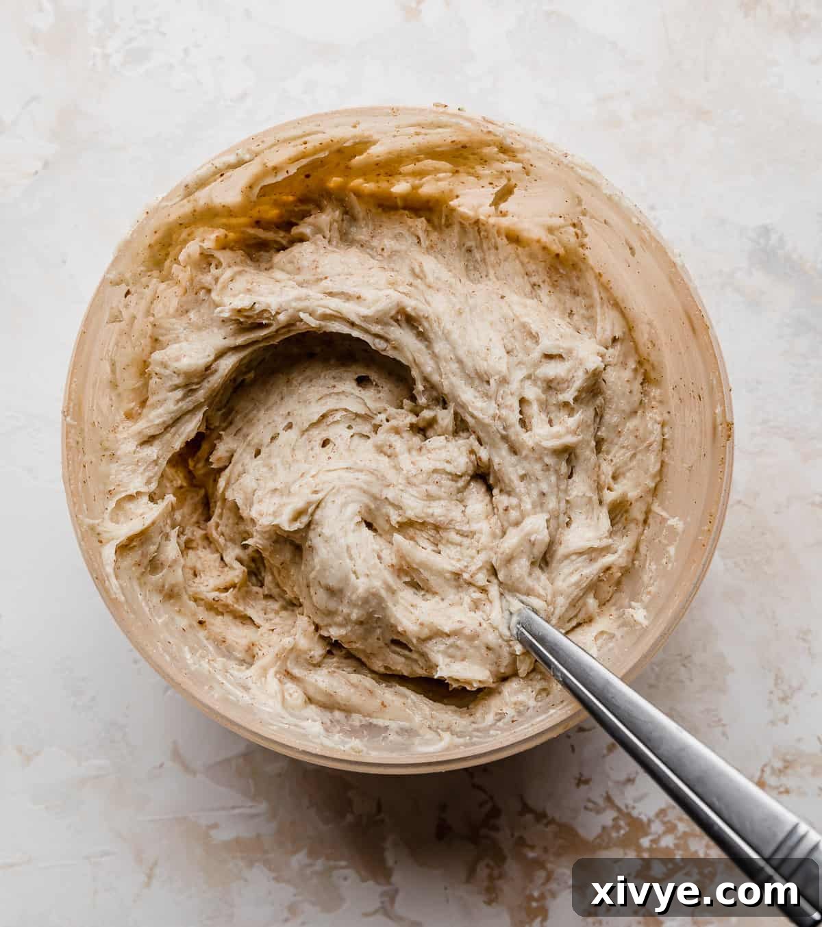 Sunshine Pineapple Pecan Carrot Cake 5 Toasted pecan buttercream in a beige colored bowl on a white background.