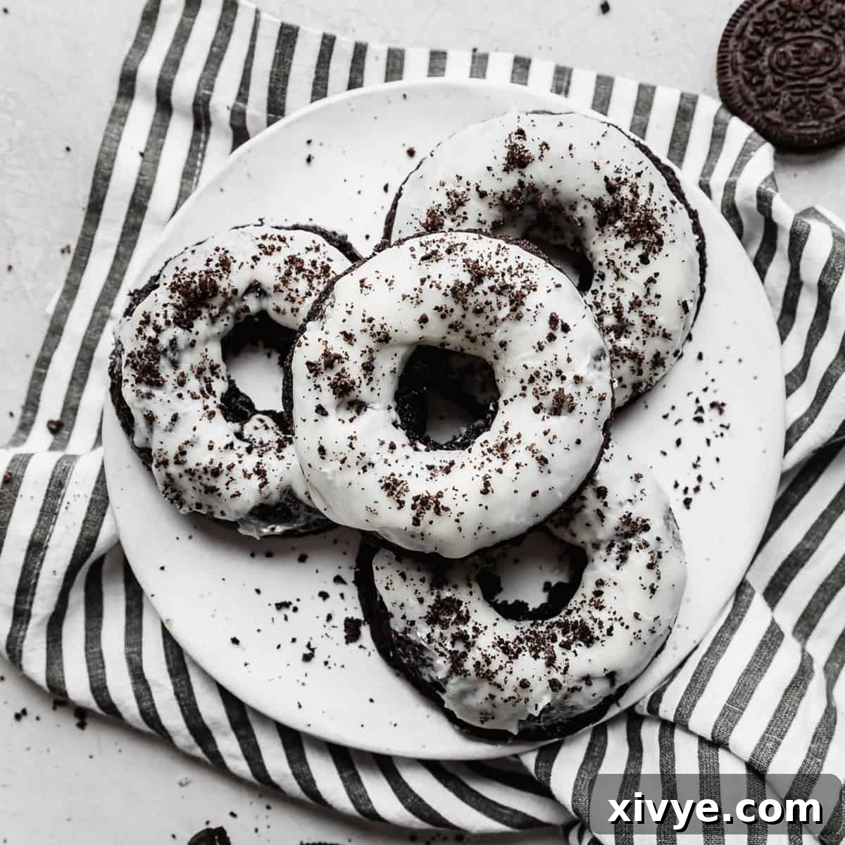 Fluffy, dark Oreo Donuts, freshly baked and glazed, resting on a striped napkin.
