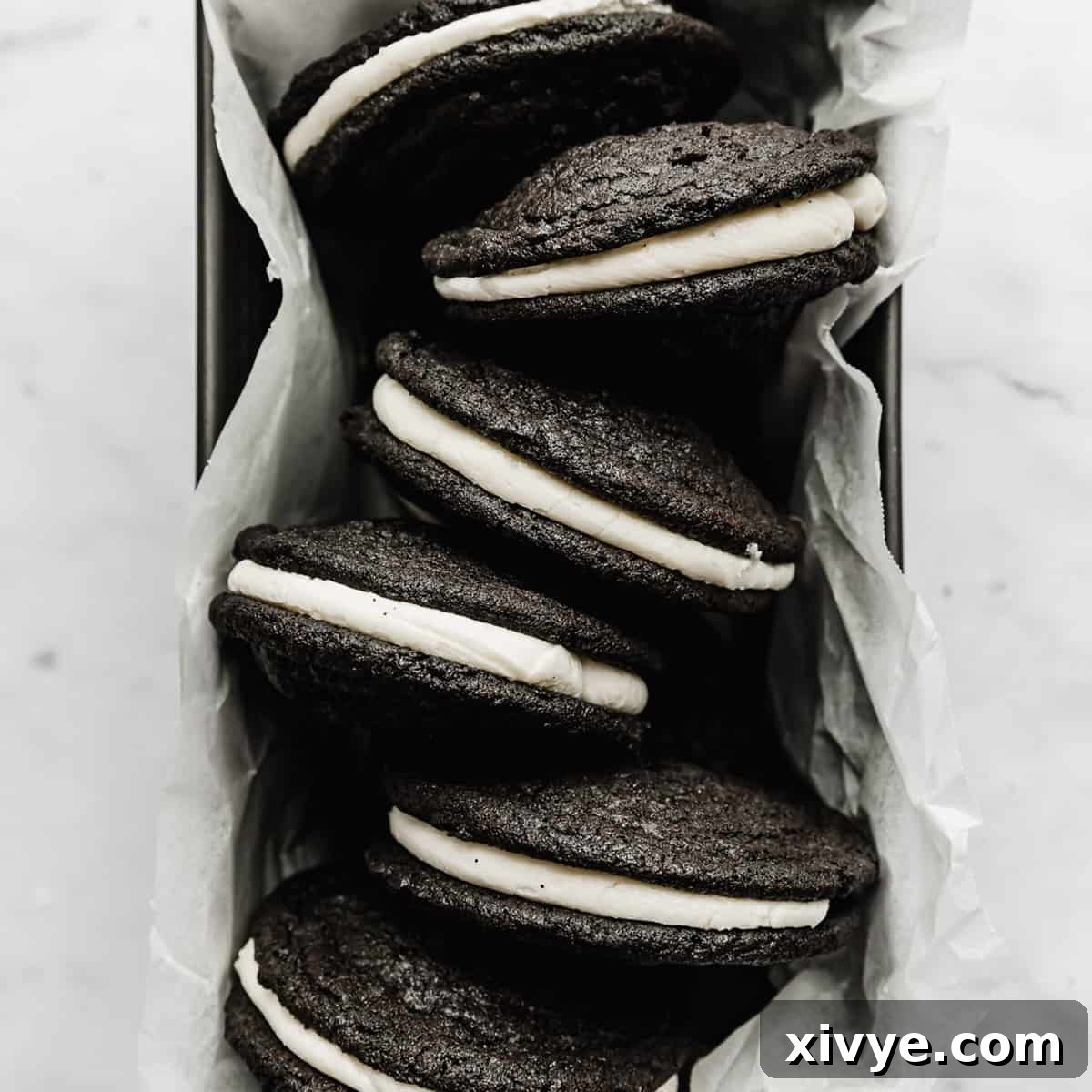 Delicious Homemade Oreo Sandwich Cookies neatly arranged in a parchment-lined bread pan, ready to be enjoyed.