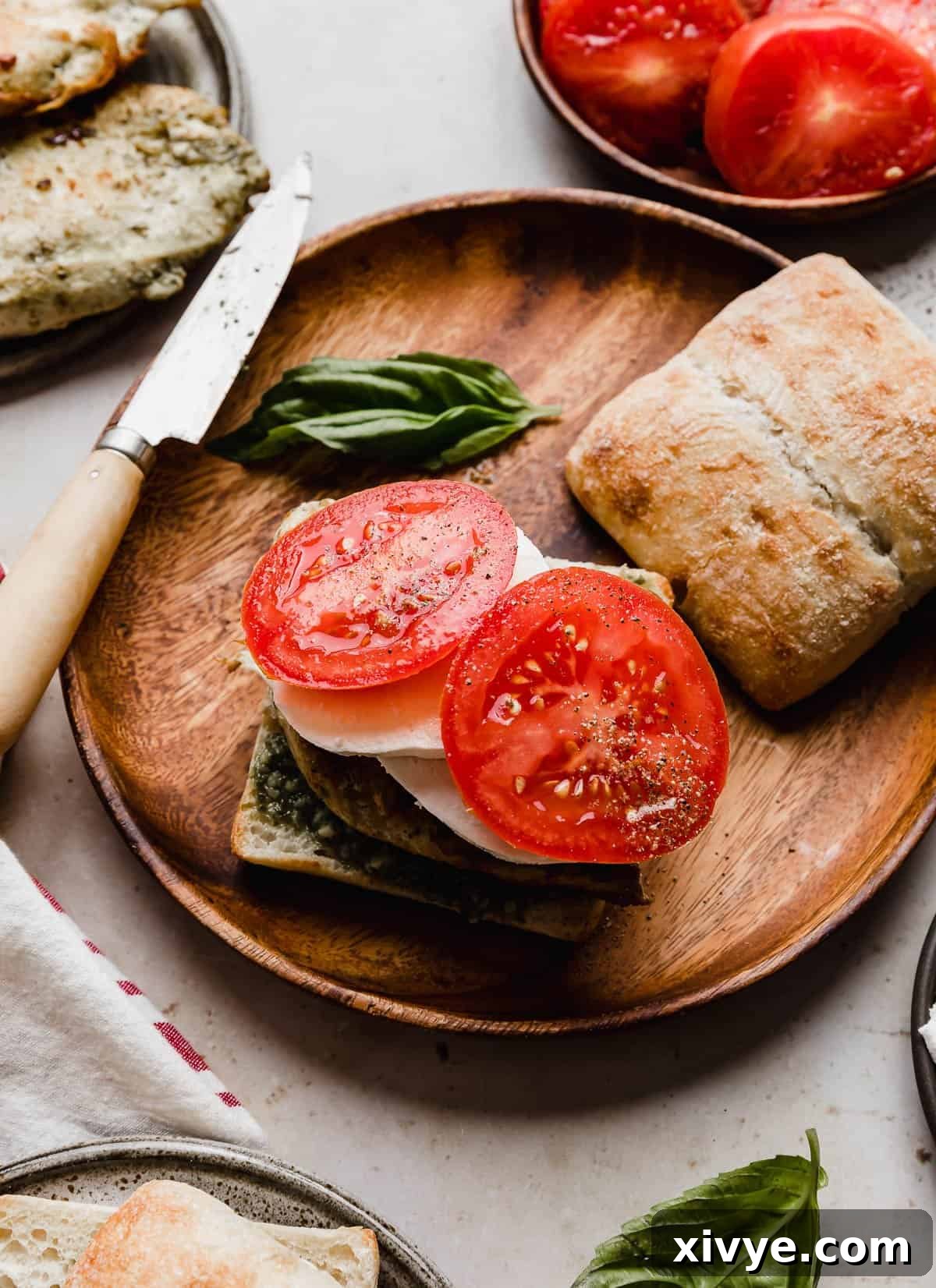 Gourmet Caprese Chicken Sandwich 7 Two slices of fresh tomato on a Chicken Caprese Sandwich, adding a burst of color and juiciness.