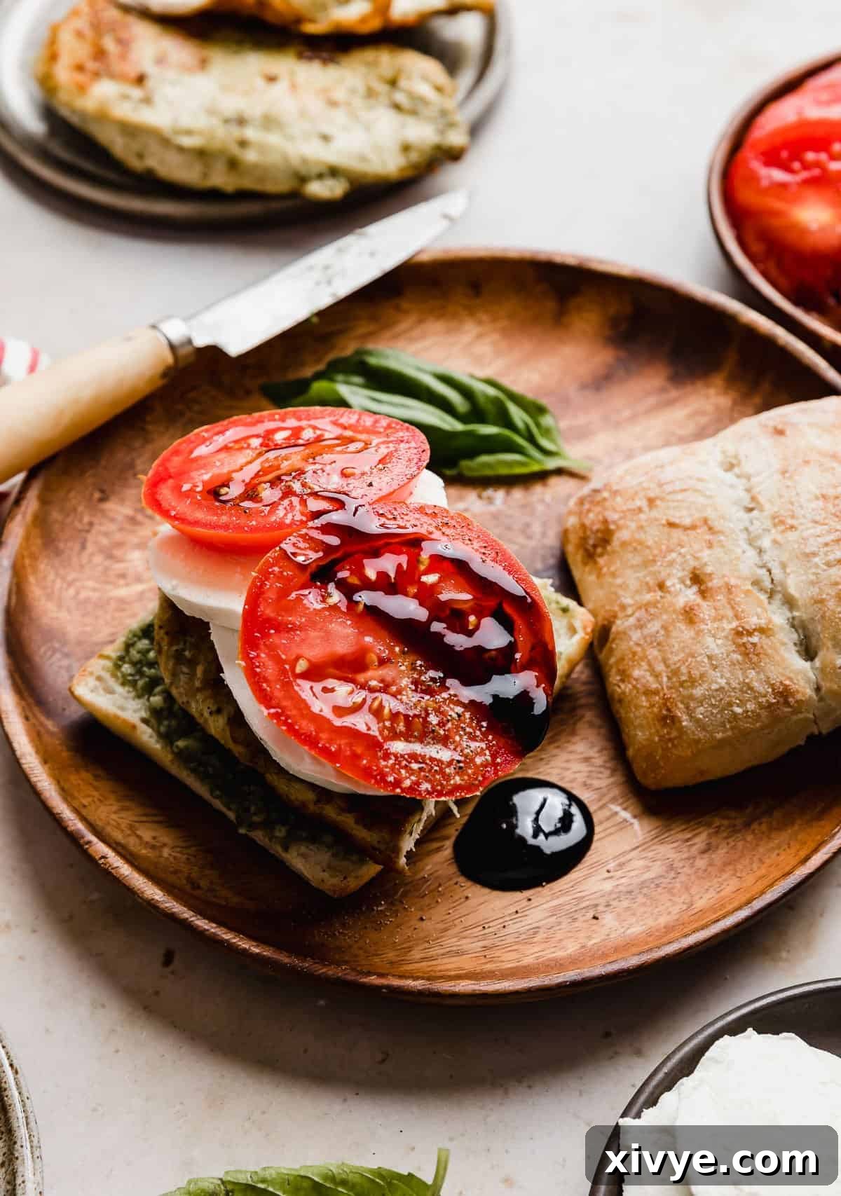 Gourmet Caprese Chicken Sandwich 9 Balsamic glaze dripping off a fresh tomato on a Chicken Caprese Sandwich on artisan bread, showcasing the richness of the glaze.