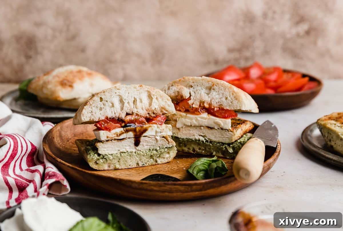 Gourmet Caprese Chicken Sandwich 10 A Chicken Caprese Sandwich on artisan bread on a round wooden plate, beautifully presented.