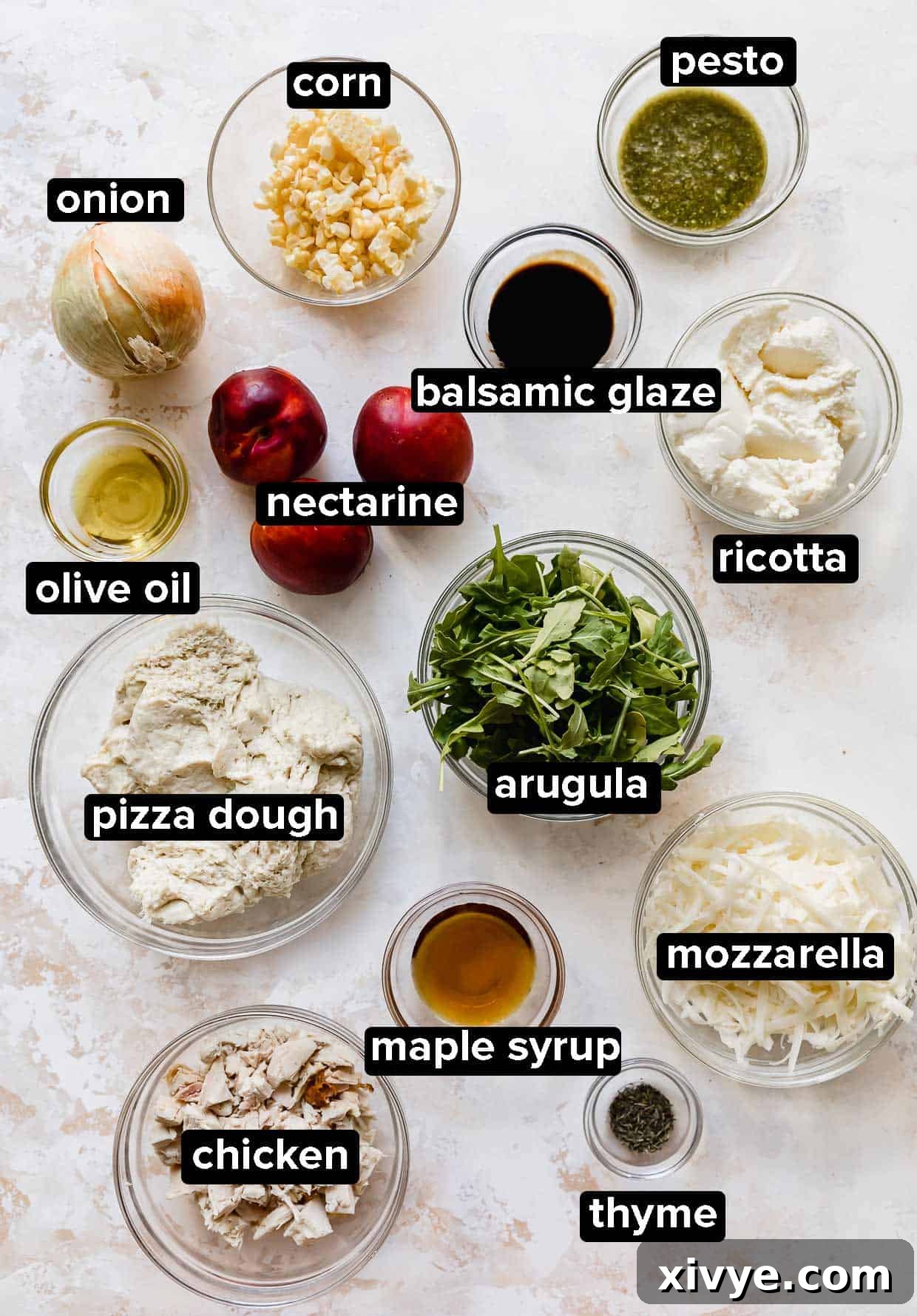 Peppery Rocket Pesto Pizza 3 Arugula Pizza ingredients portioned into glass bowls on a white background, ingredients include: ricotta, nectarines, chicken, thyme, corn, onion, pesto.