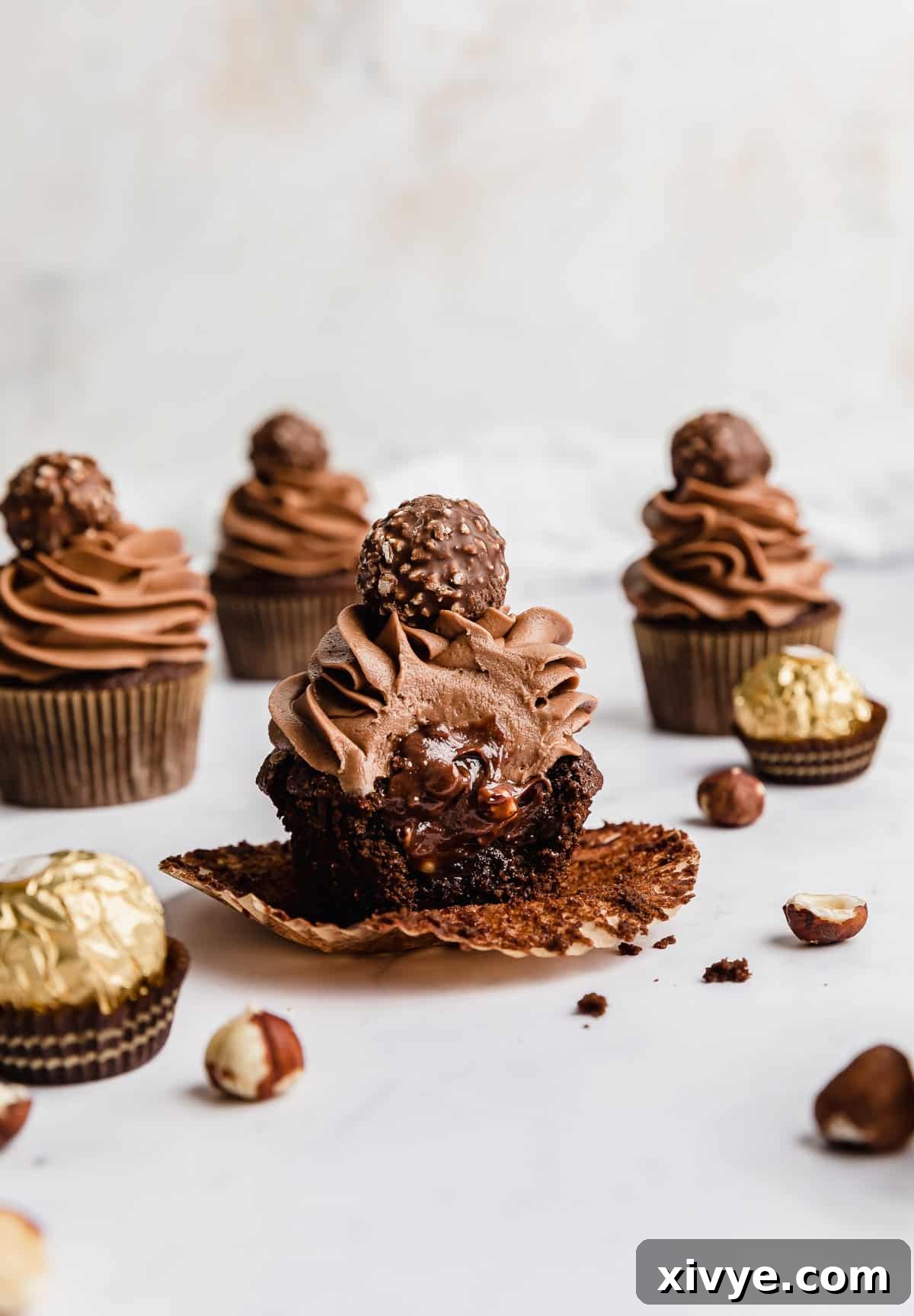 A Ferrero Rocher Cupcake with a bite taken out of it showing the inside of the cupcake filled with Nutella.