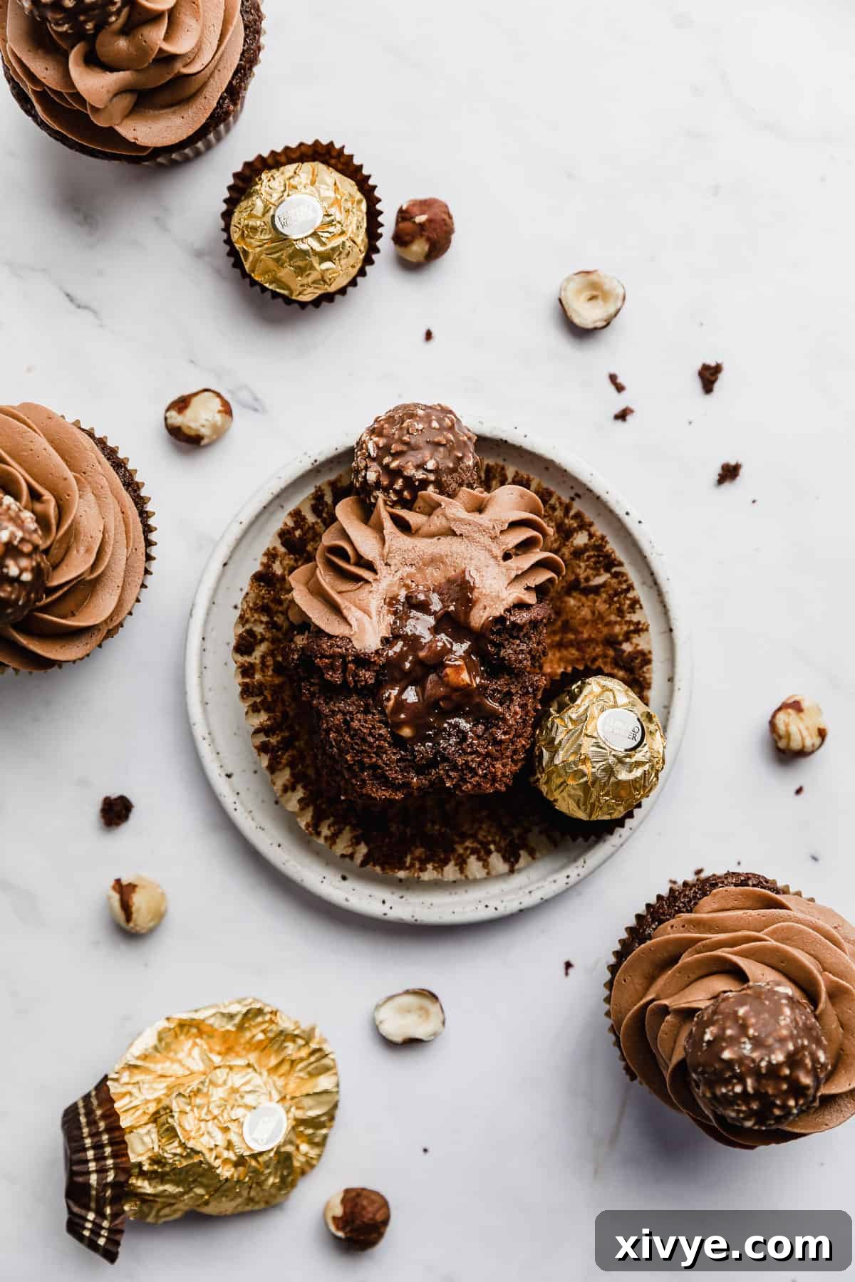 Half of a Ferrero Rocher Cupcake on a white plate with Nutella spilling from the center of the cupcake.