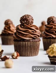 Ferrero Rocher Cupcakes topped with a swirl of chocolate frosting and a Ferrero Rocher candy.