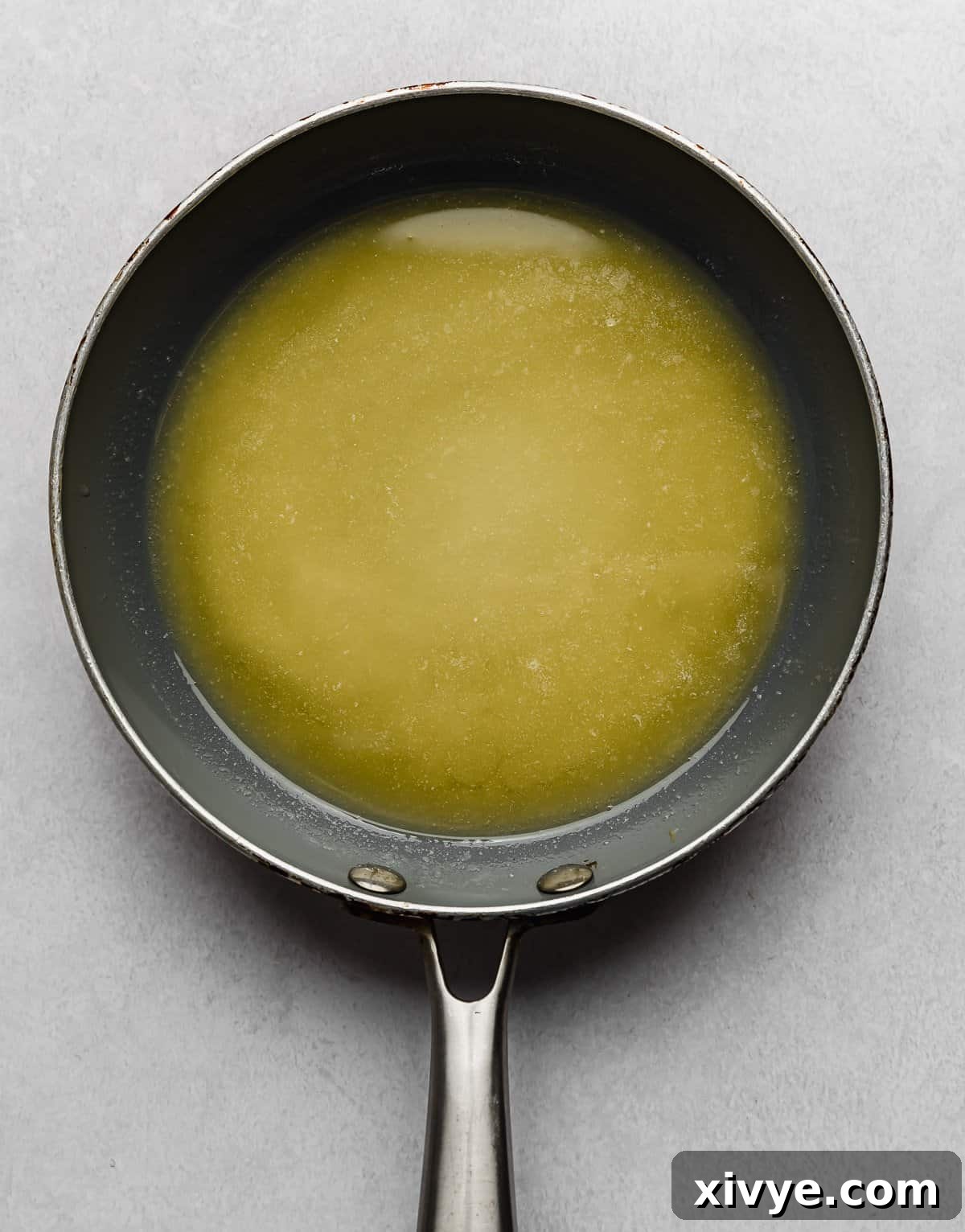 The Secret to Nutty Butter 6 Melted butter in a grey skillet on a light grey background.