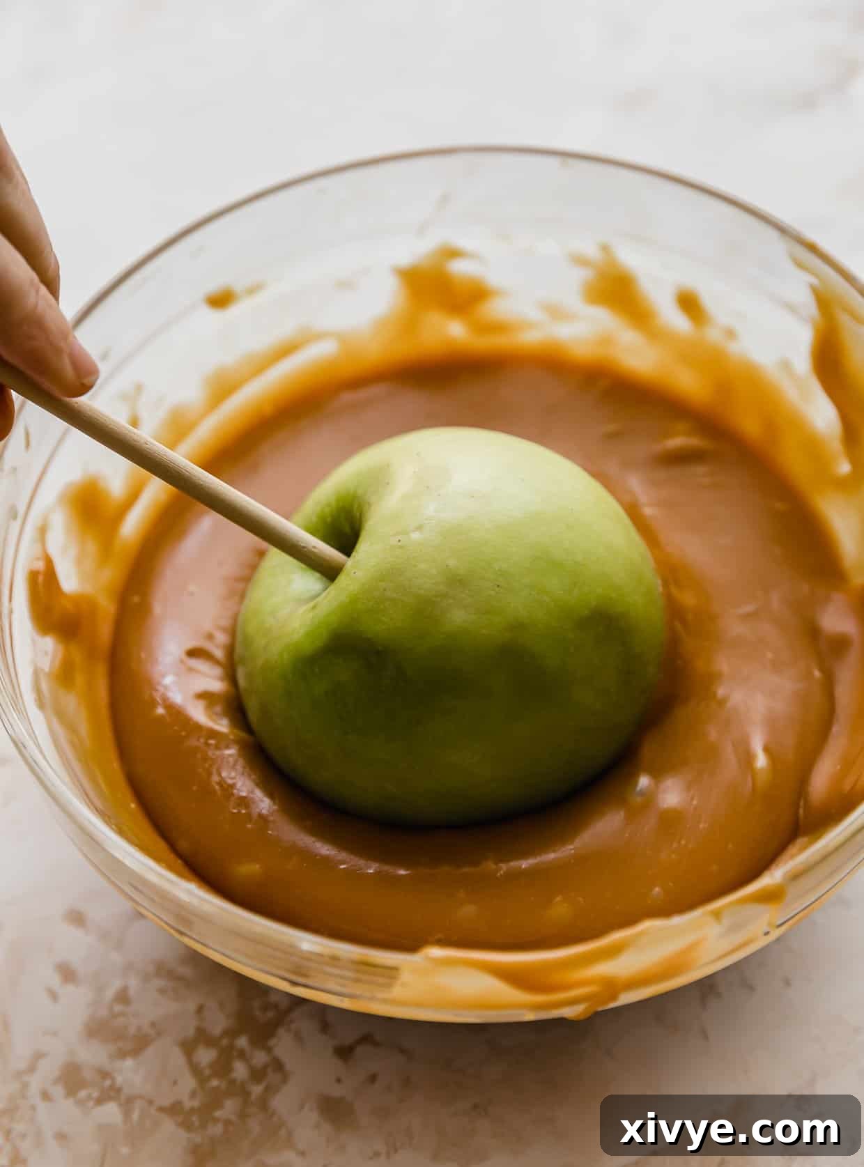 Caramel Apple Pie Fusion 6 A green Granny Smith apple being dunked in caramel.