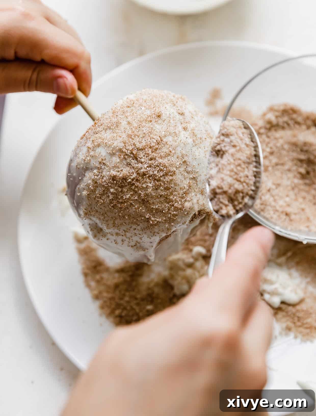 Caramel Apple Pie Fusion 10 A cinnamon sugar mixture being sprinkled overtop a white chocolate coated apple pie caramel apple.