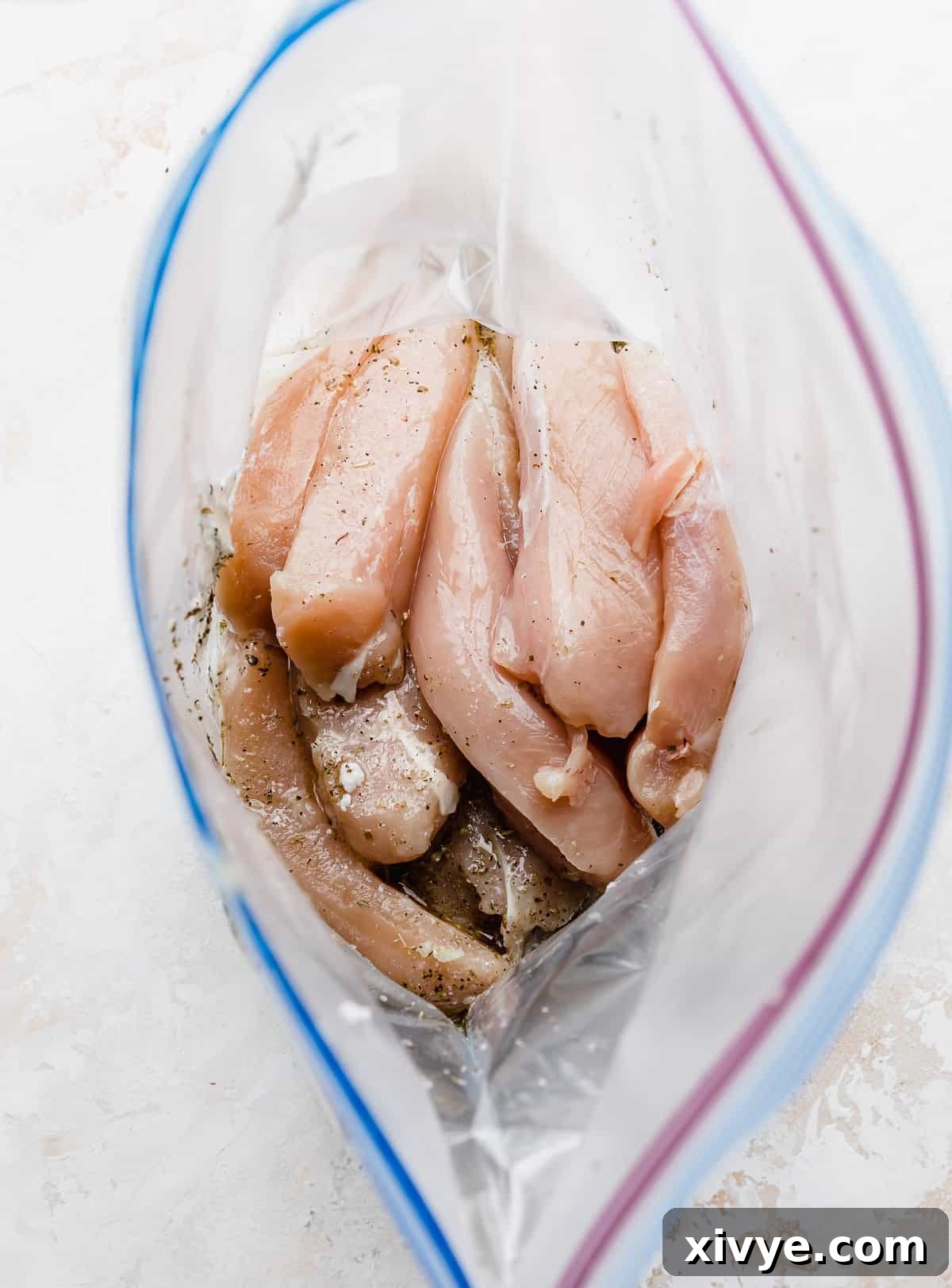 A ziplock bag with raw chicken tenders in it.