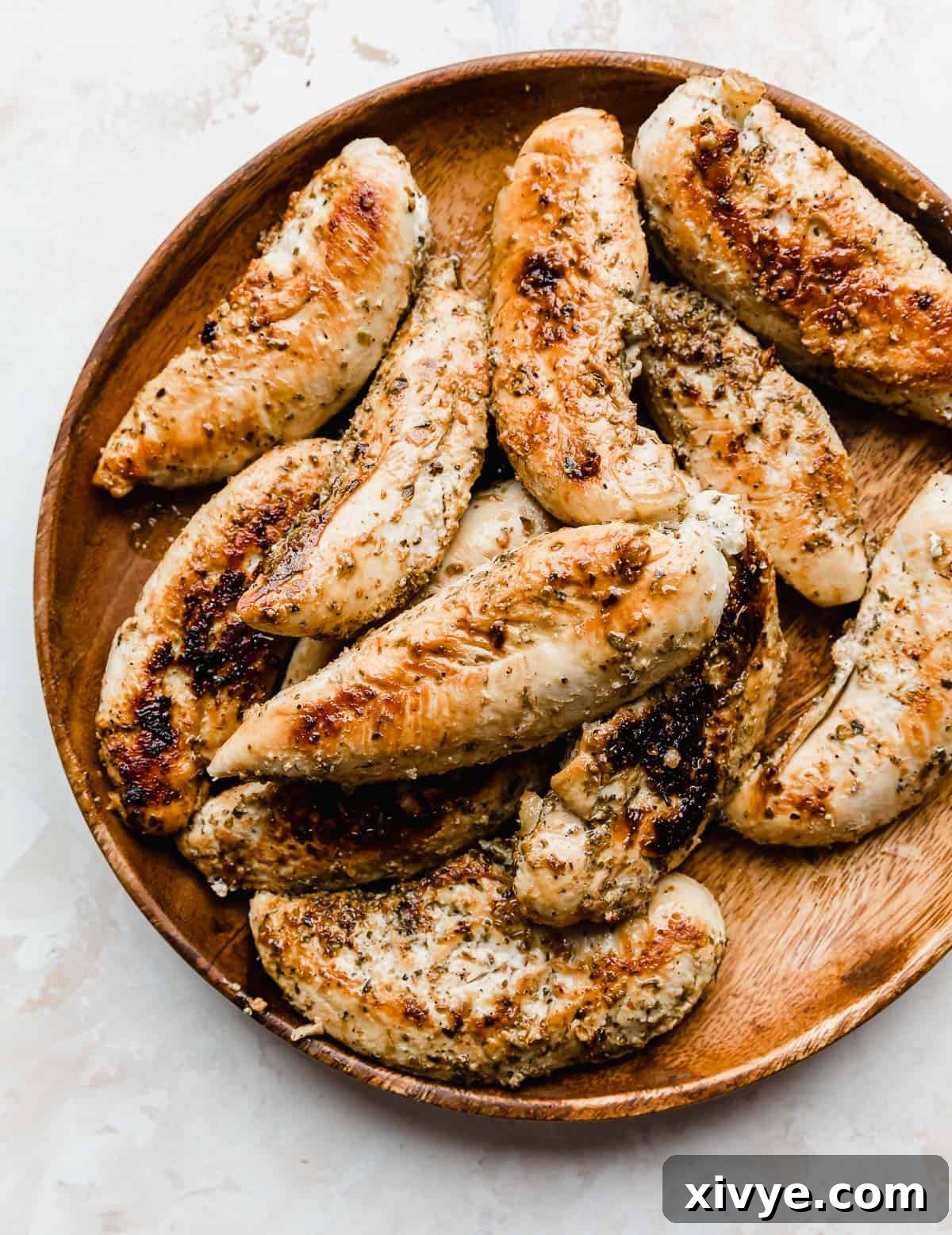 A brown plate with golden brown cooked chicken tenders on it, on a white background.