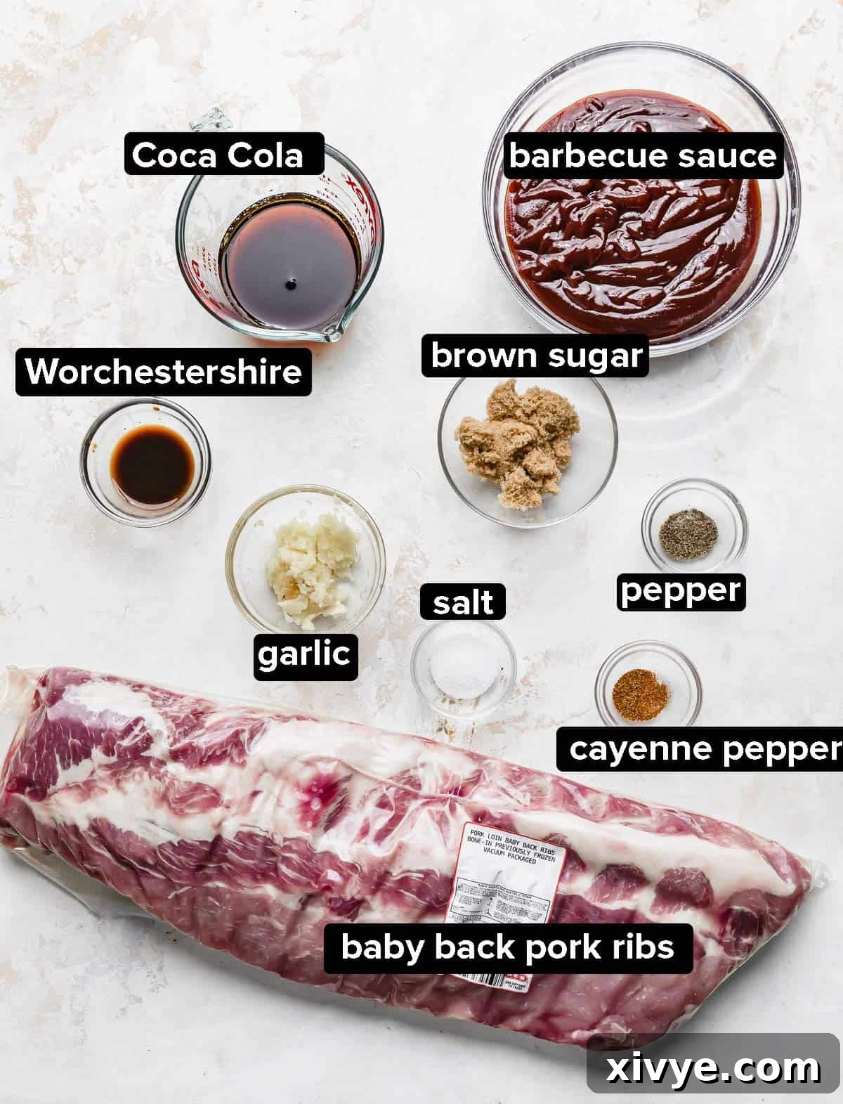 A selection of ingredients used to make Coca Cola Slow Cooker Ribs, including barbecue sauce, Coca Cola, brown sugar, garlic, Worcestershire sauce, and cayenne pepper, artfully arranged on a clean white background.