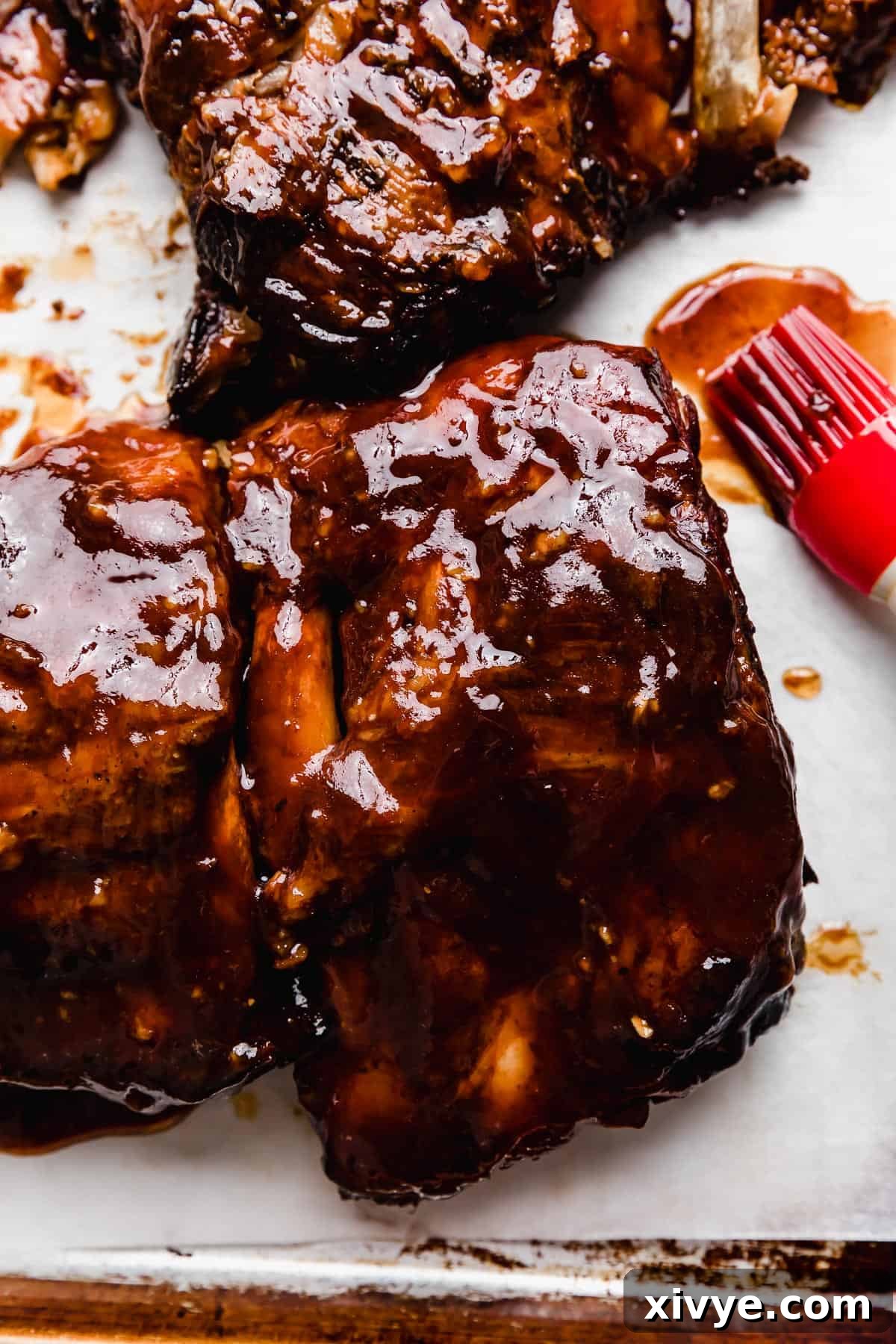 Beautifully glazed Coca Cola Ribs covered in a rich, dark brown and red colored sauce, presented on a pristine white background.