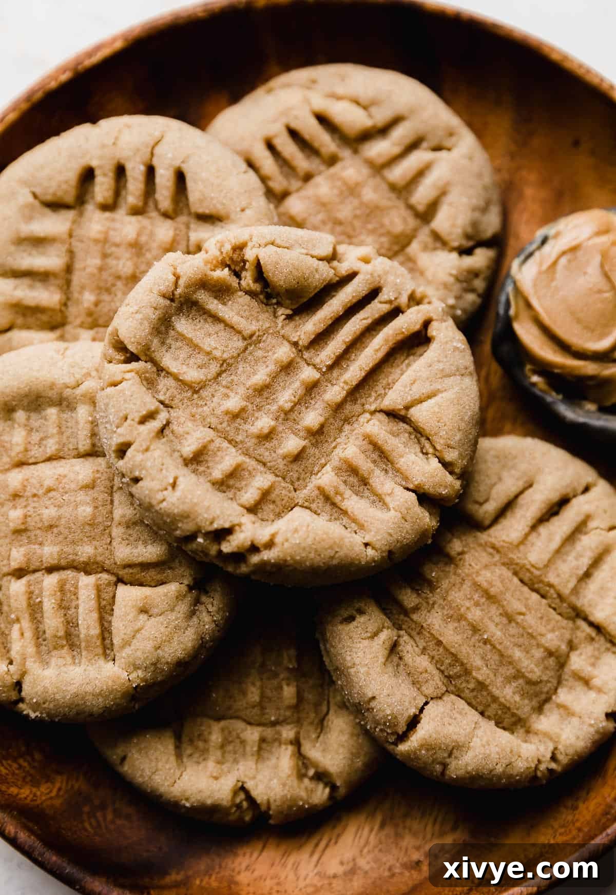 Crumbl's Iconic Peanut Butter Perfection 2 A brown plate with copycat Crumbl Classic Peanut Butter Cookies on it with a criss cross fork imprint in each cookie.