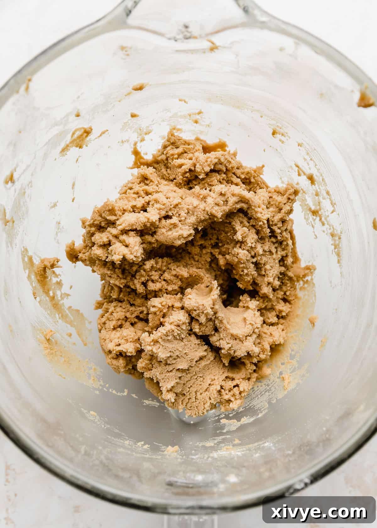 Crumbl's Iconic Peanut Butter Perfection 4 A close up photo of Crumbl Classic Peanut Butter Cookie dough in a glass bowl.