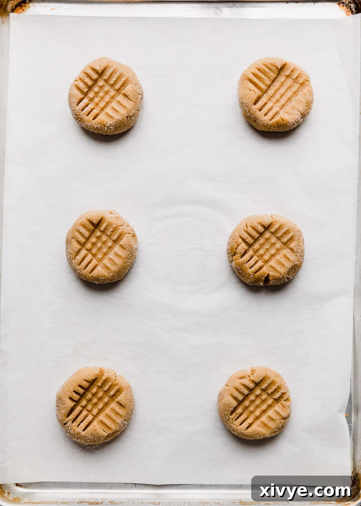 Crumbl's Iconic Peanut Butter Perfection 6 Six copycat Crumbl Classic Peanut Butter Cookies on a white parchment lined baking sheet.