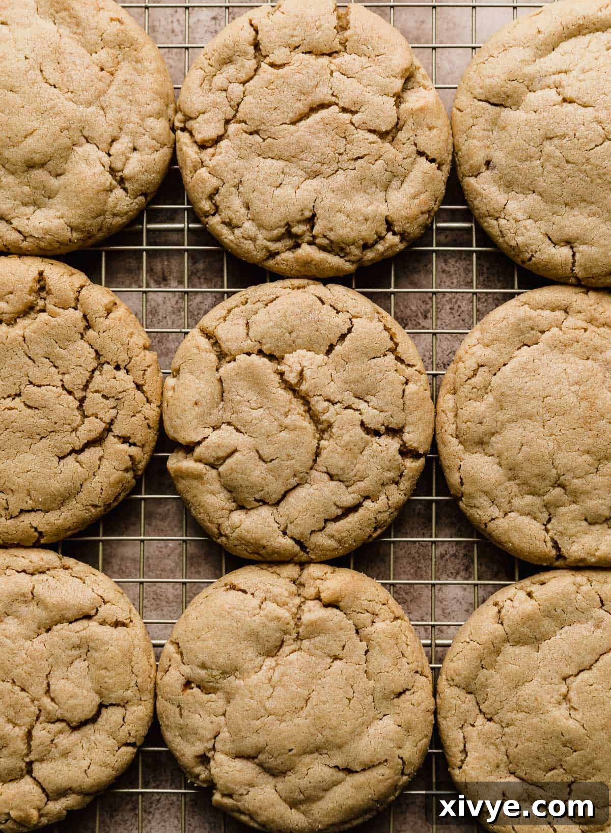 A batch of warm, baked Crumbl Peanut Butter Cup Cookies arranged on a wire cooling rack, ready for topping.