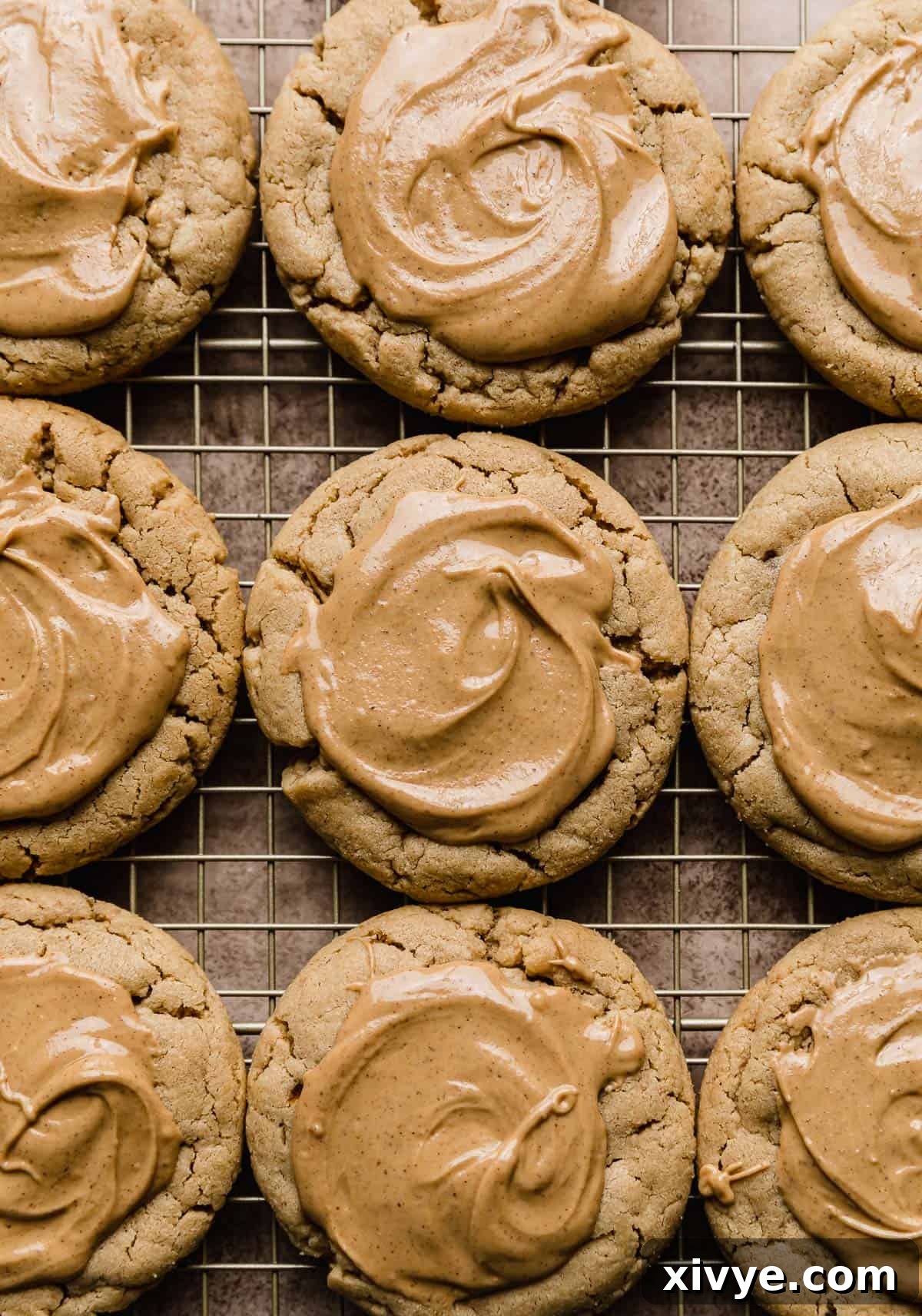 Several peanut butter cookies, each generously topped with a smooth, glossy melted peanut butter layer, arranged on a wire rack for cooling.
