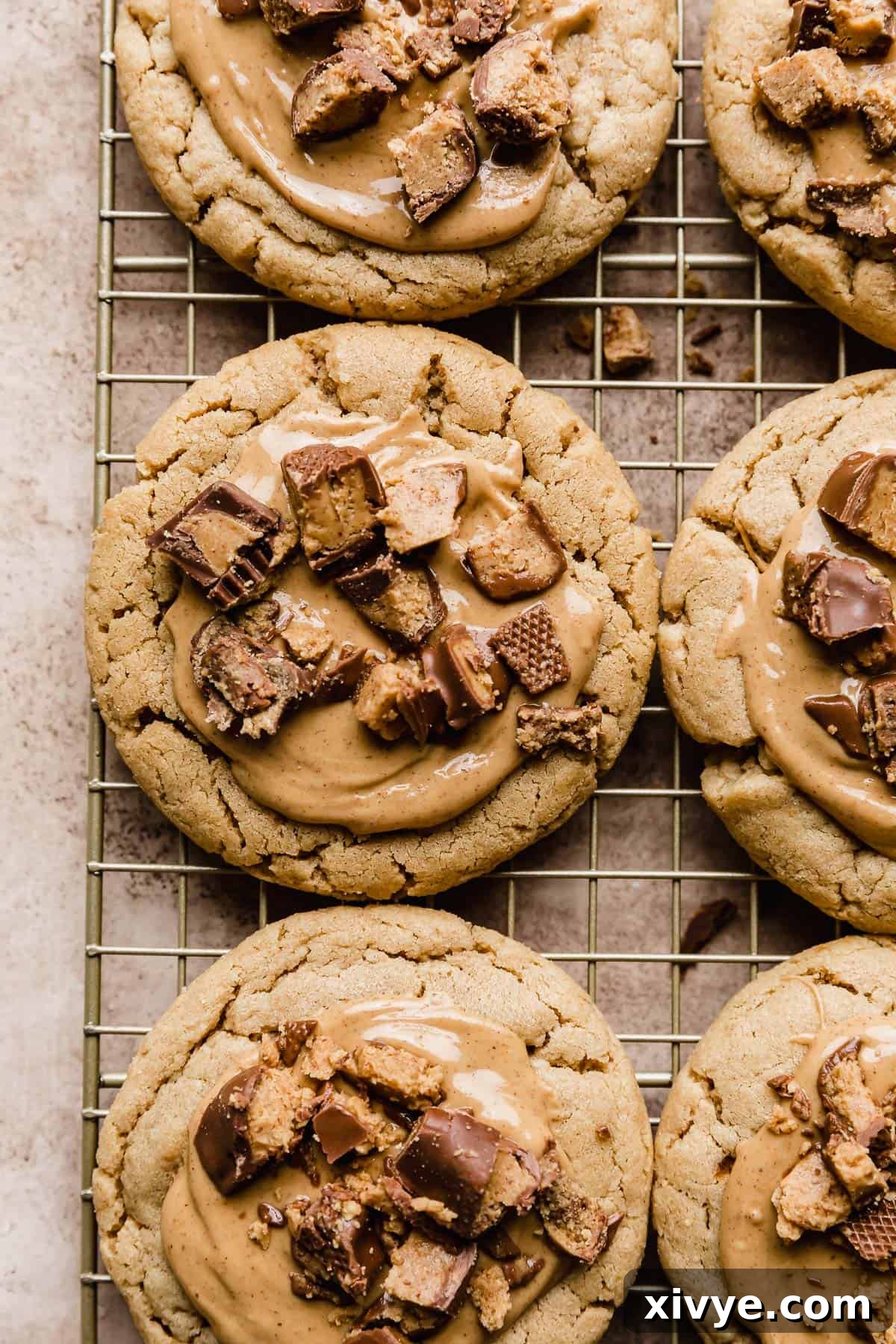 A pristine display of Crumbl Peanut Butter Cup Cookies elegantly arranged on a wire cooling rack, set against a clean white background.