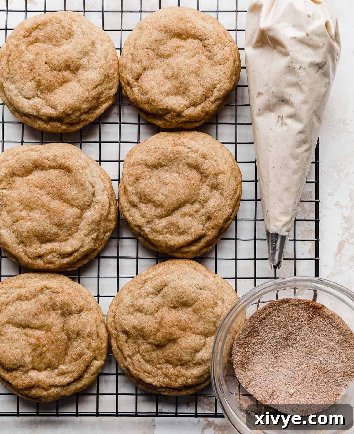 Homemade Crumbl Churro Cookie Perfection 7 A batch of freshly baked churro cookies rests on a wire cooling rack, their golden edges and soft centers visible as they cool down.