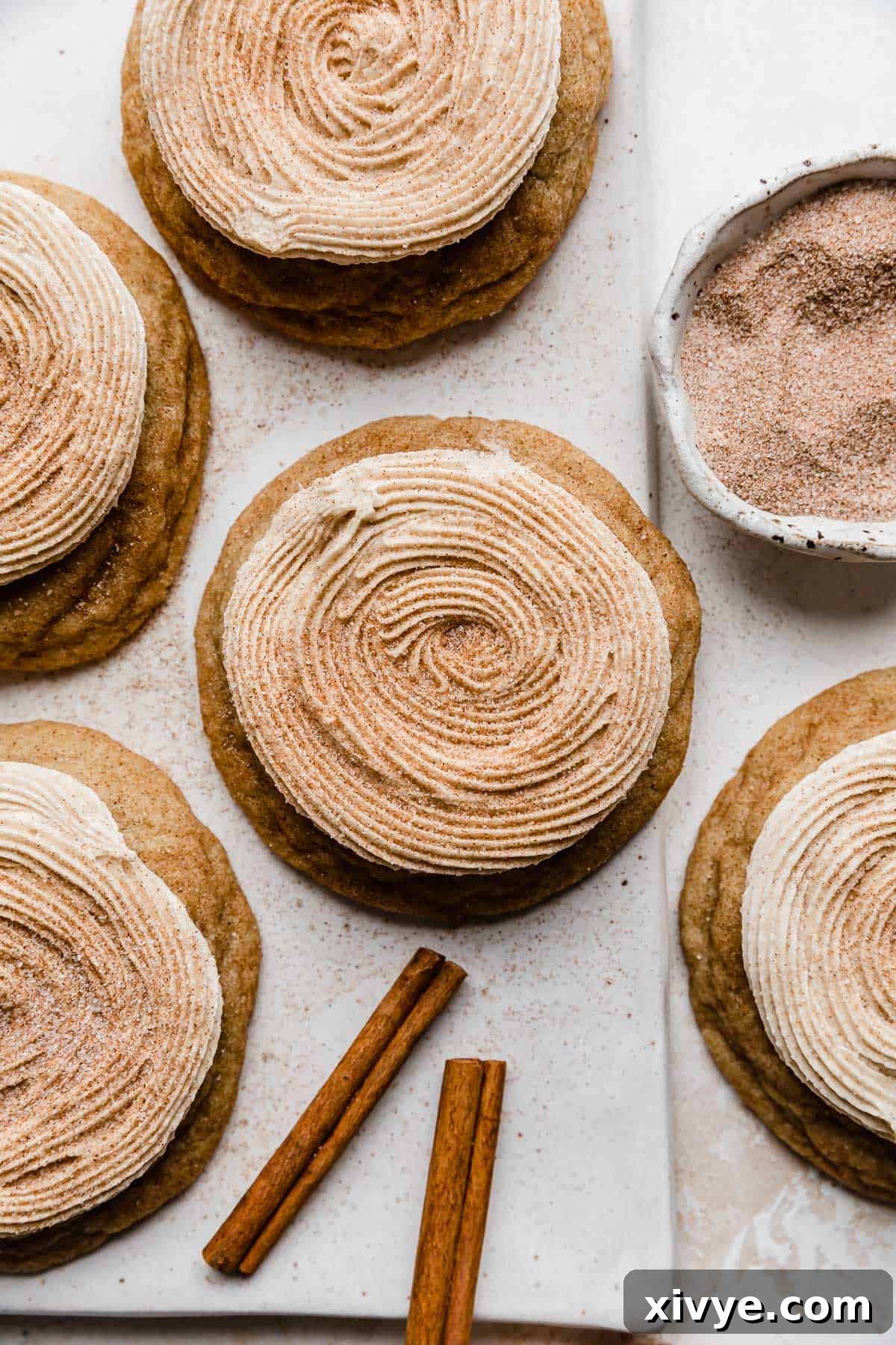 Homemade Crumbl Churro Cookie Perfection 8 A pristine white background features a collection of frosted churro cookies, each adorned with a perfect swirl of cinnamon buttercream and a generous dusting of cinnamon sugar.