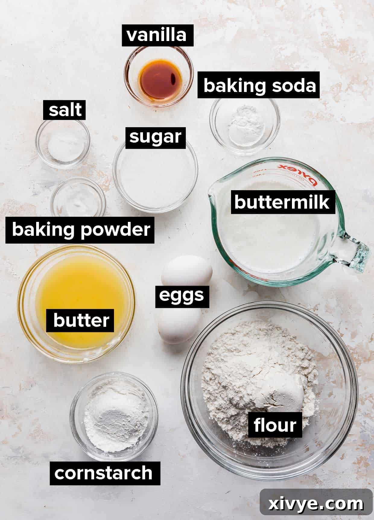 Various ingredients including flour, eggs, butter, and buttermilk are neatly arranged on a counter, ready for making crispy buttermilk waffles.