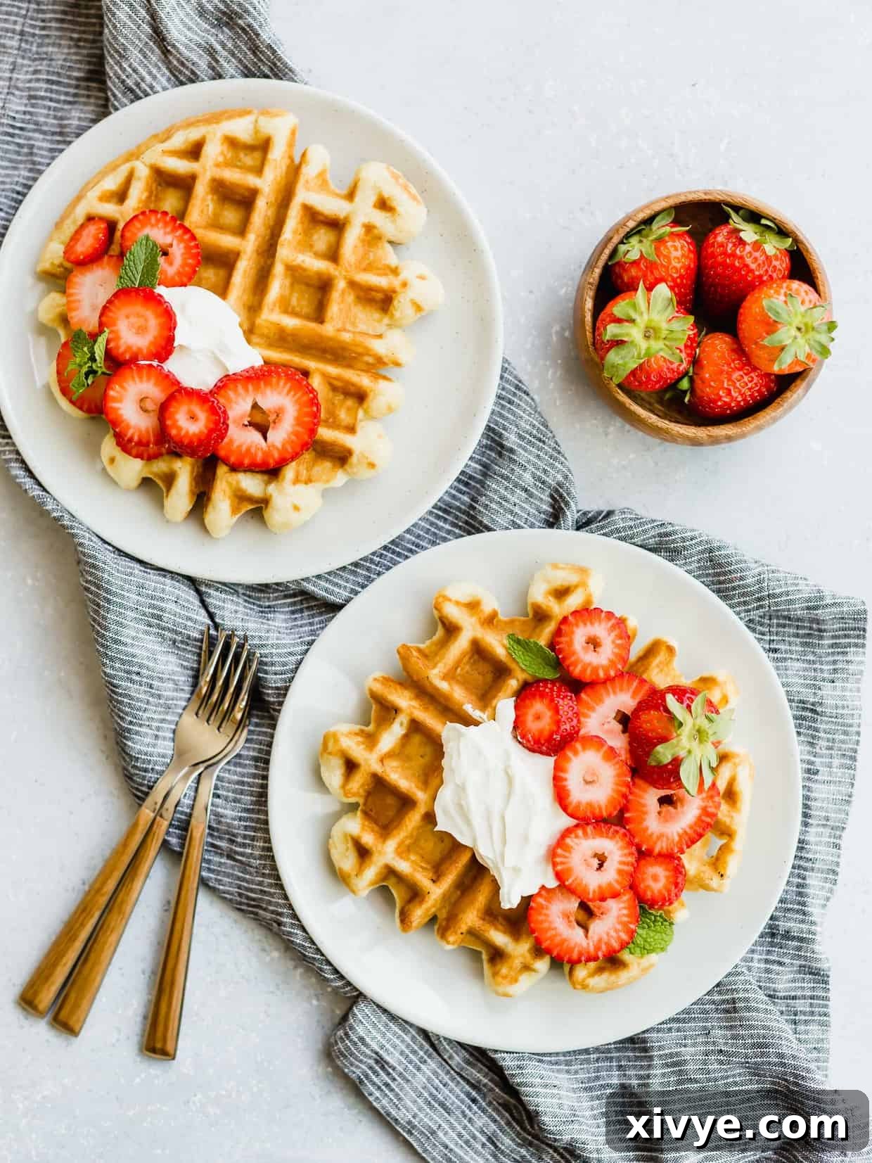 An overhead shot showcasing two perfectly cooked buttermilk waffles, elegantly topped with whipped cream and fresh strawberries, ready for serving.