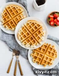 Three buttermilk waffles with three forks to the side.