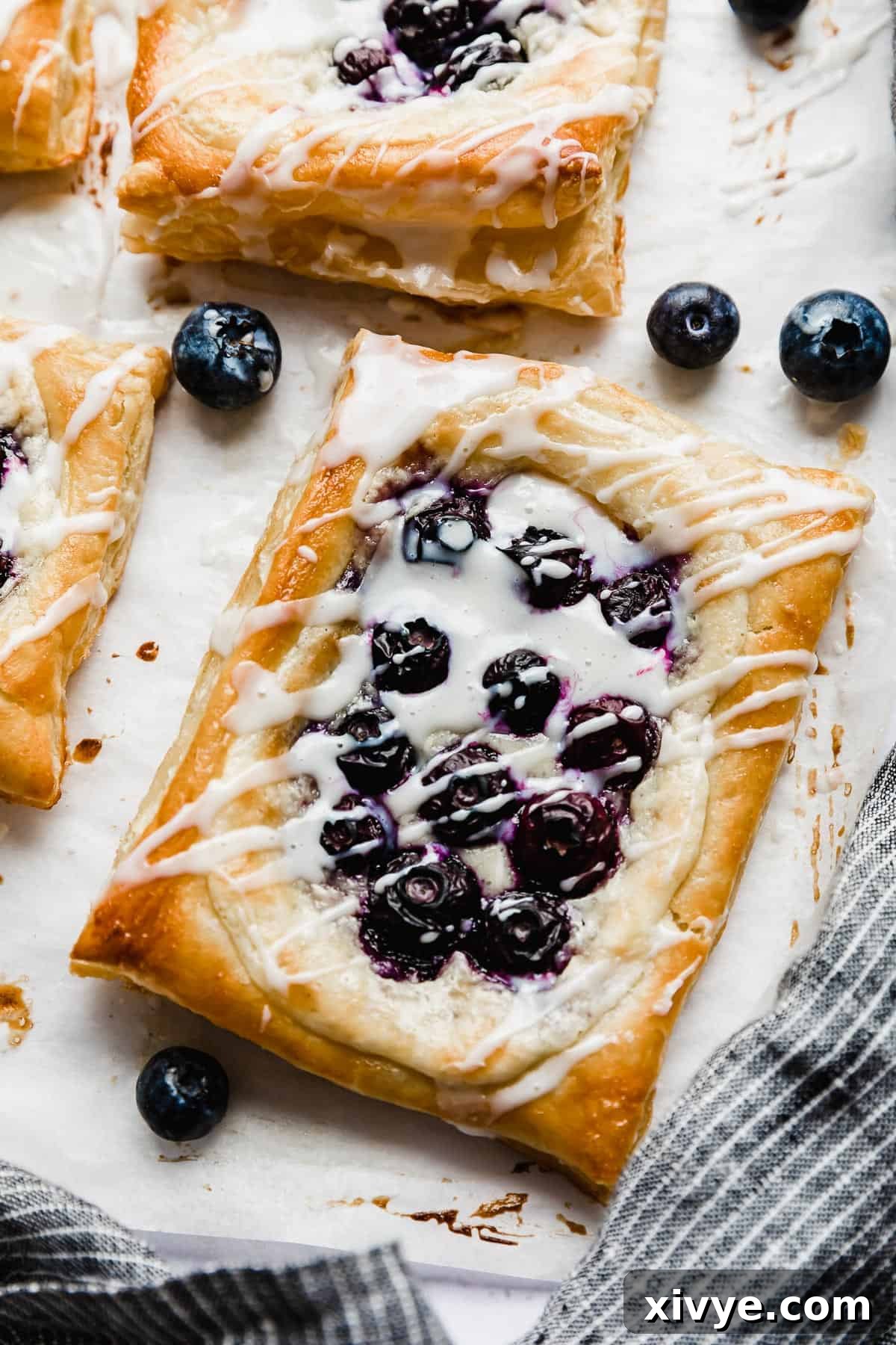 Flaky Blueberry Dream 2 A rectangle blueberry danish with cream cheese filling, topped with a drizzle of white glaze.