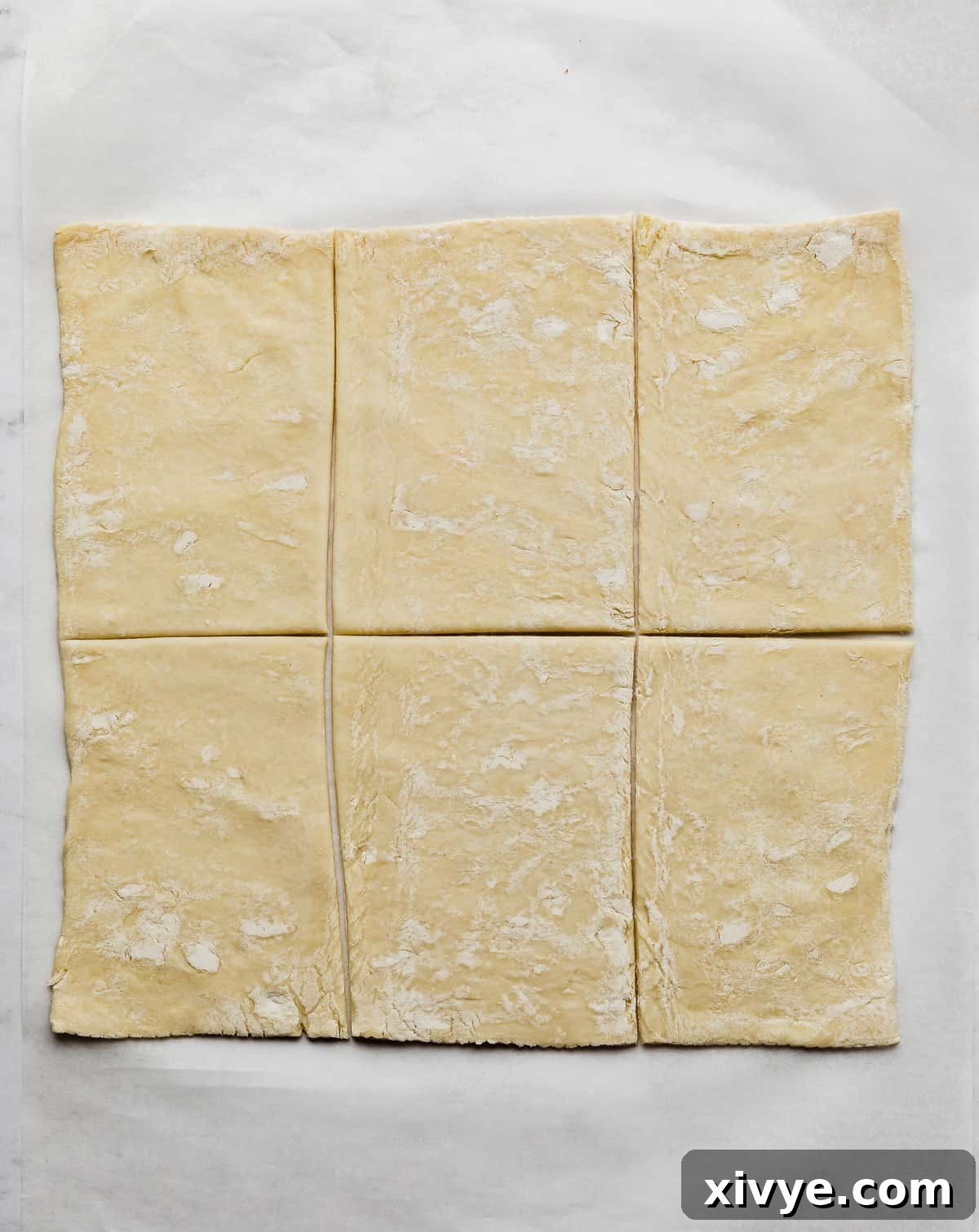 Flaky Blueberry Dream 4 A rectangle of puff pastry cut into 6 rectangular pieces on a white background.