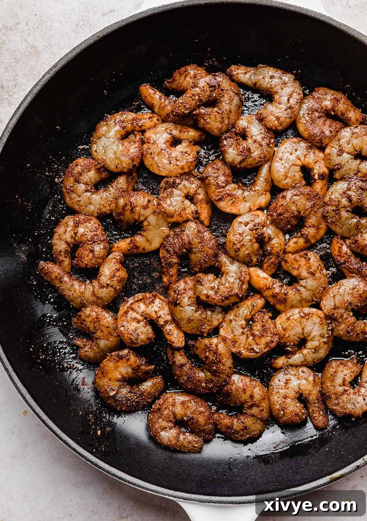 Blackened Shrimp, richly coated in dried spices, sizzling in a black skillet.