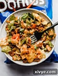 Ultimate Doritos Taco Salad 11 A tempting plate of Catalina dressing taco salad rests atop a blue bag of Cool Ranch Doritos, highlighting its irresistible appeal.