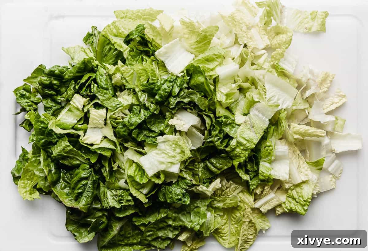Ultimate Doritos Taco Salad 7 Freshly chopped romaine lettuce arranged on a white cutting board, showcasing its vibrant green color and crisp texture.