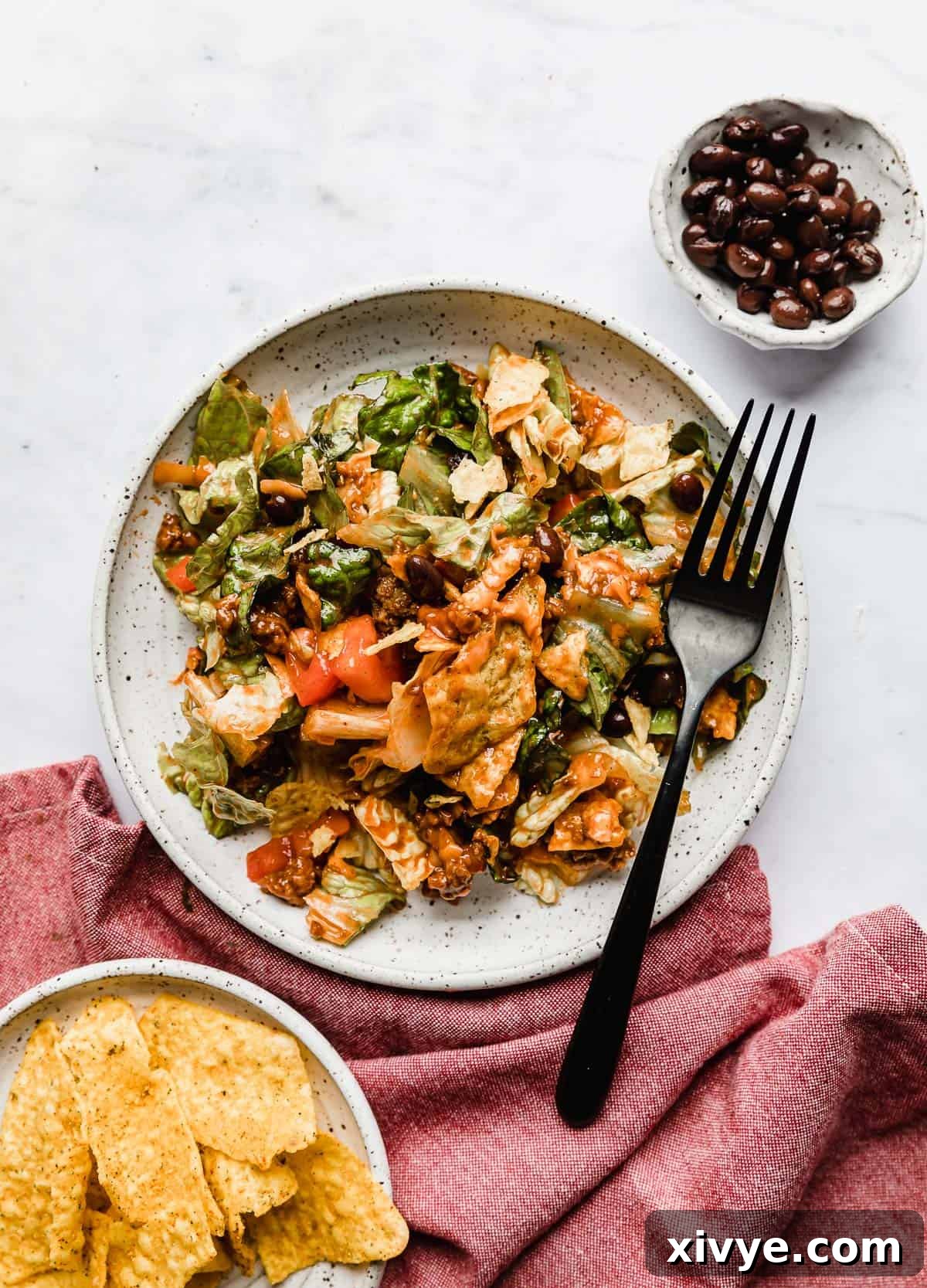 Ultimate Doritos Taco Salad 9 A beautifully presented taco salad with creamy Catalina dressing, served on a white plate with a festive red napkin underneath, highlighting its fresh appeal.