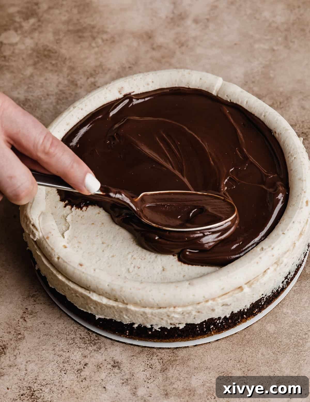 Chocolate ganache filling being spread overtop a frosted S'mores Cake layer.
