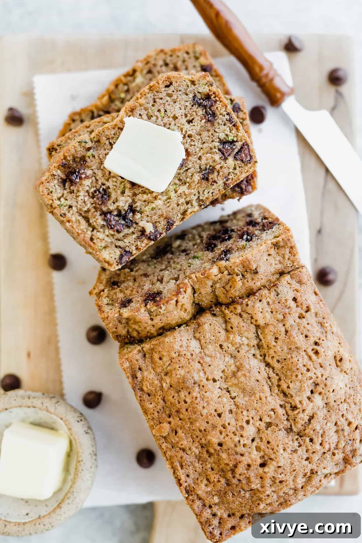 Overhead view of sliced chocolate chip zucchini bread with a square of butter on a slice of bread.