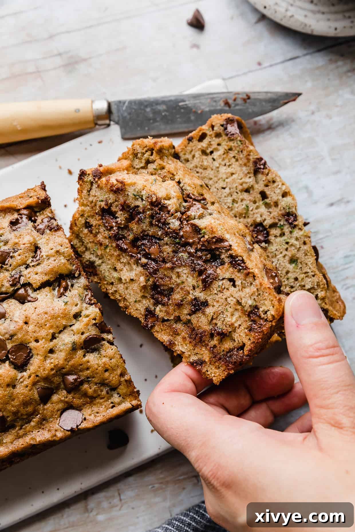 A hand grabbing a slice of chocolate chip zucchini bread.