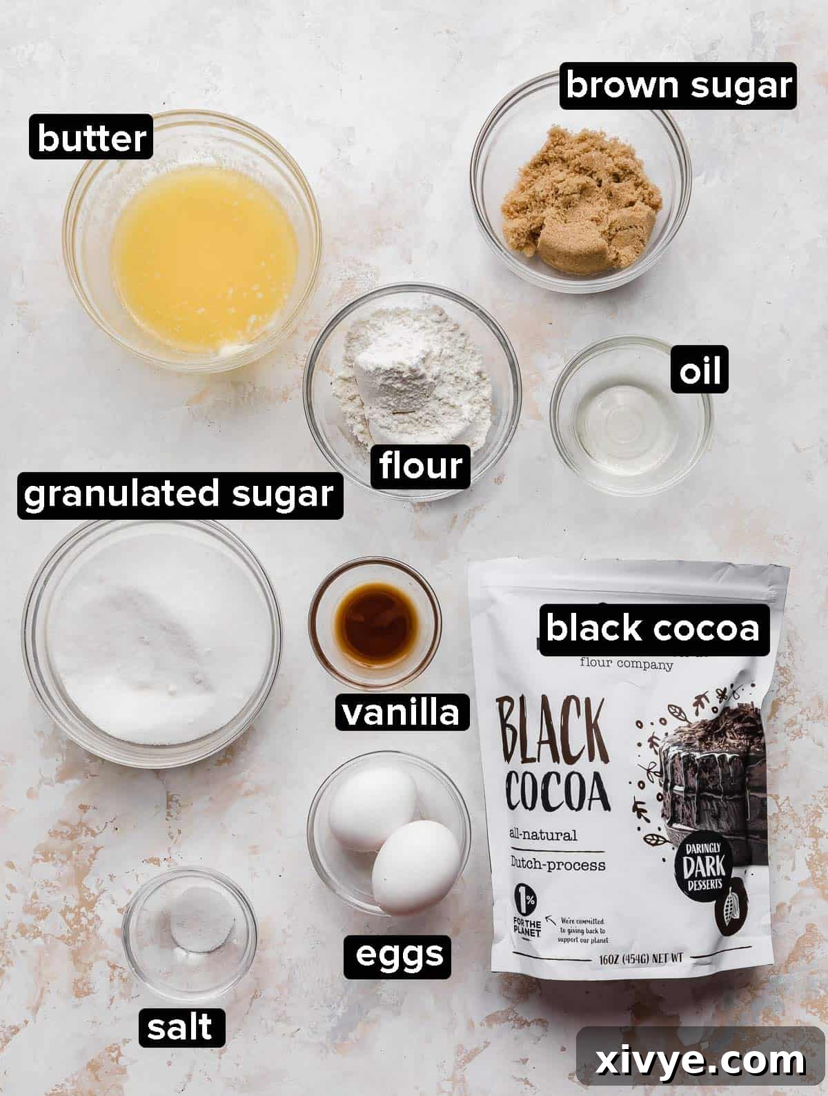 Ultimate Blackout Brownies 3 Black Cocoa Brownie ingredients portioned into glass bowls on a white textured background.